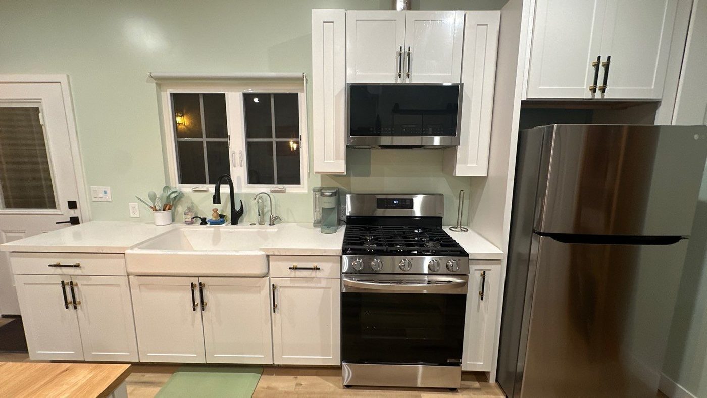 ADU kitchen with white cabinets, farmhouse sink, and gas range