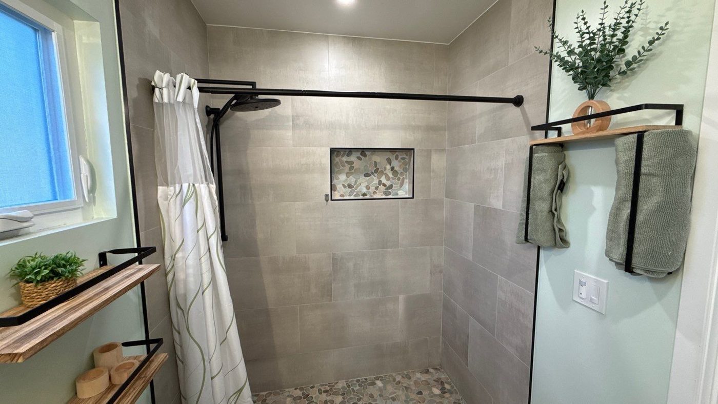 ADU bathroom shower with tile walls and pebble floor