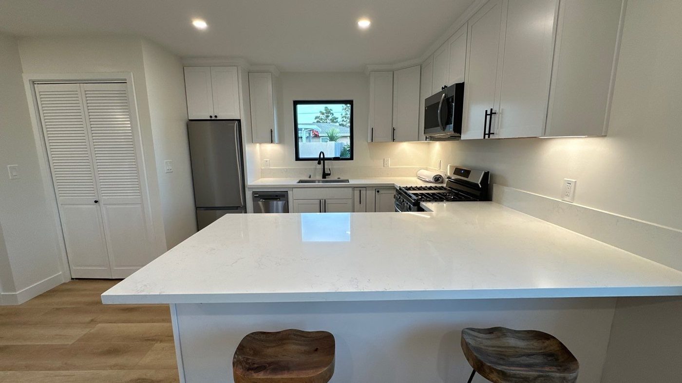 ADU kitchen with white cabinets and a quartz island with seating