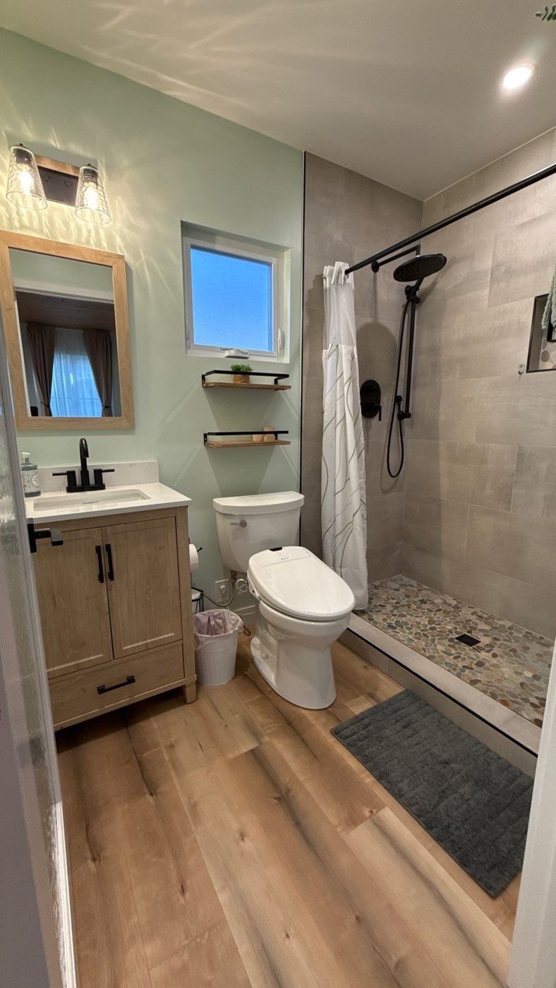 ADU bathroom with wood vanity, walk-in shower, and wood-look flooring