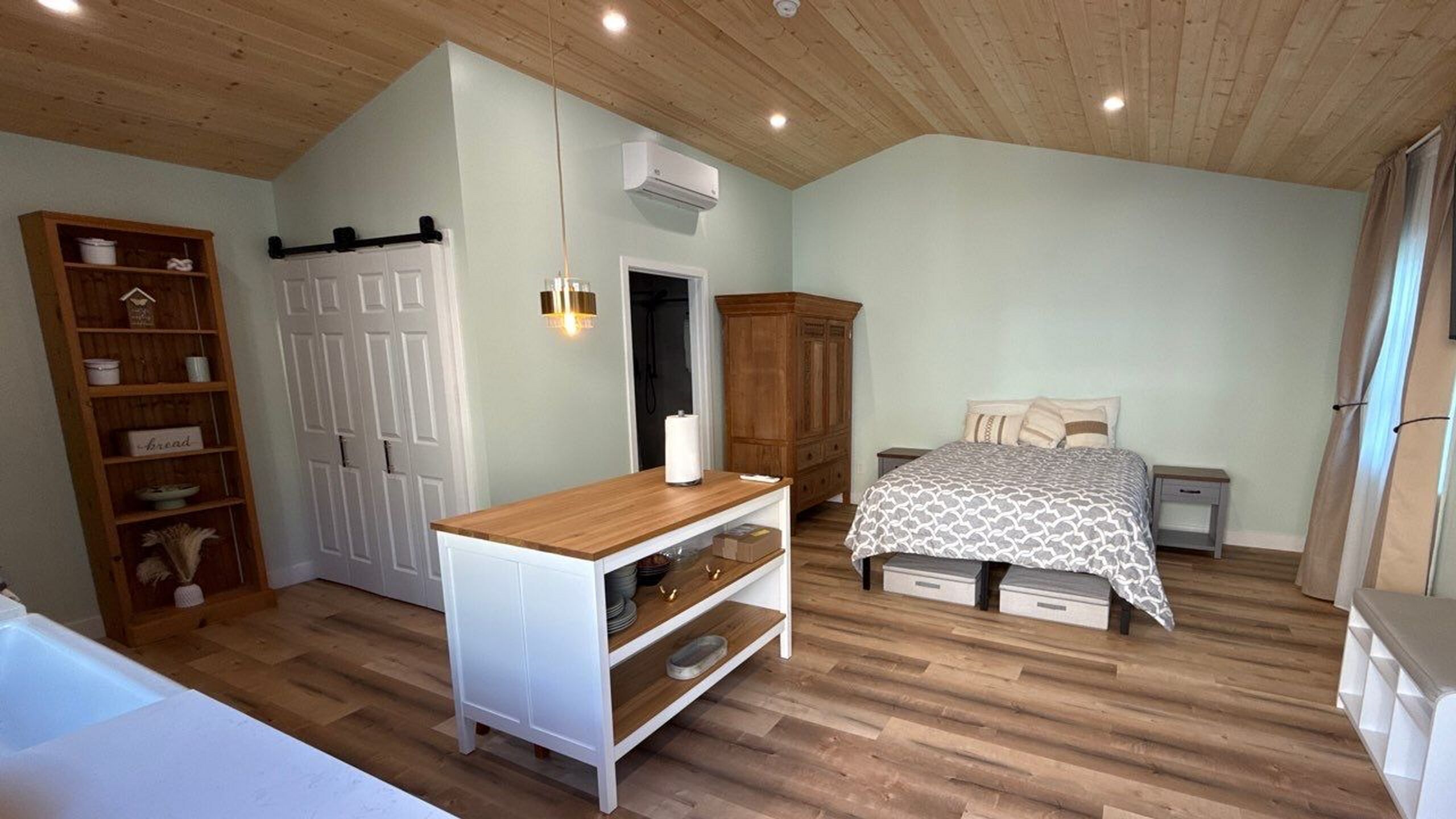 Finished ADU interior with vaulted wood ceiling, kitchen island, and sleeping area