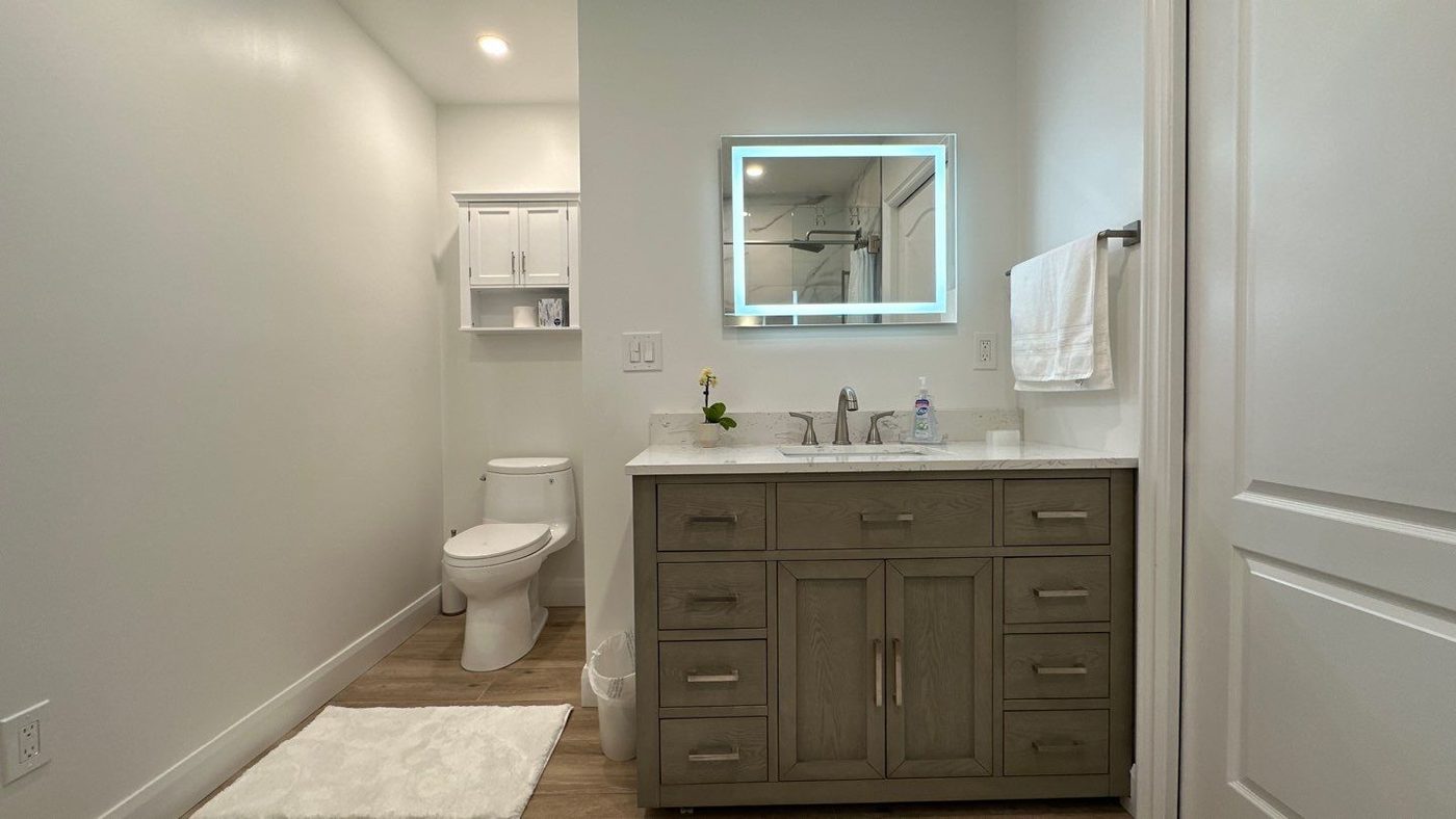 Bathroom vanity with lit LED mirror and wood-look flooring