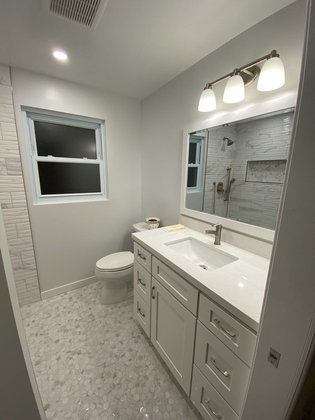 White bathroom vanity with quartz top and hexagon pebble tile floor