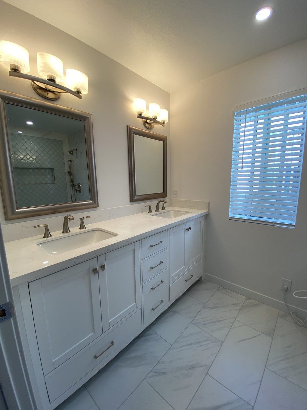 Double vanity with white cabinets and marble tile flooring