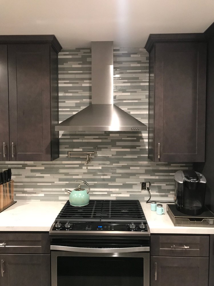 Stove, range hood, and pot filler detail with mosaic tile backsplash