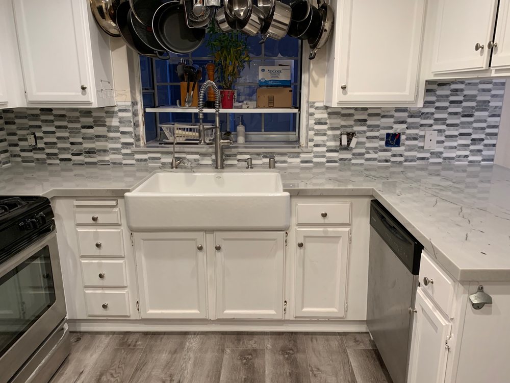Kitchen with white shaker cabinets, marble countertops, and mosaic tile backsplash