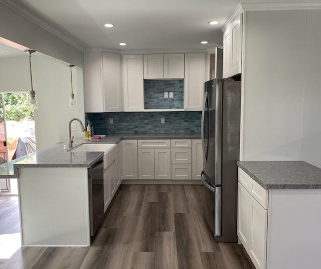 Kitchen remodel with white cabinets, blue mosaic backsplash, and stainless refrigerator