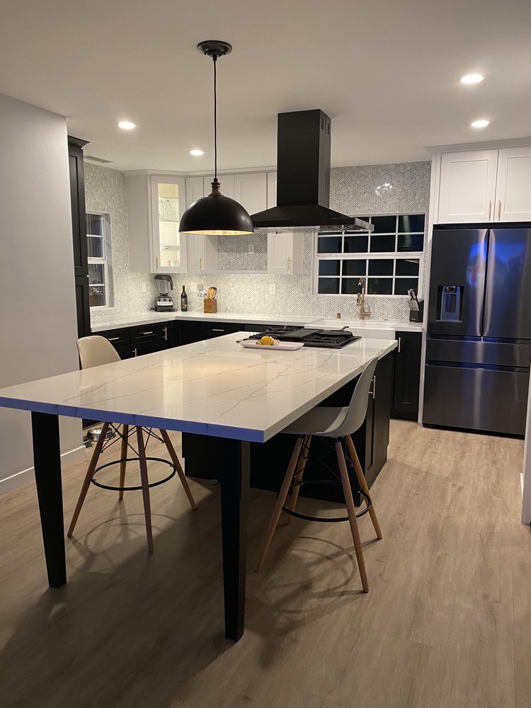 Remodeled kitchen with white and black cabinetry, a marble island, and stainless appliances